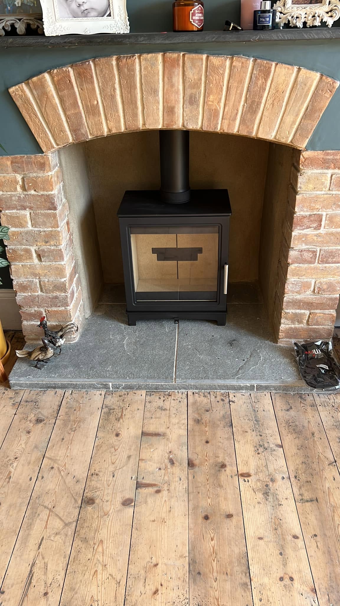 Contemporary black stove installed in a brick arched fireplace