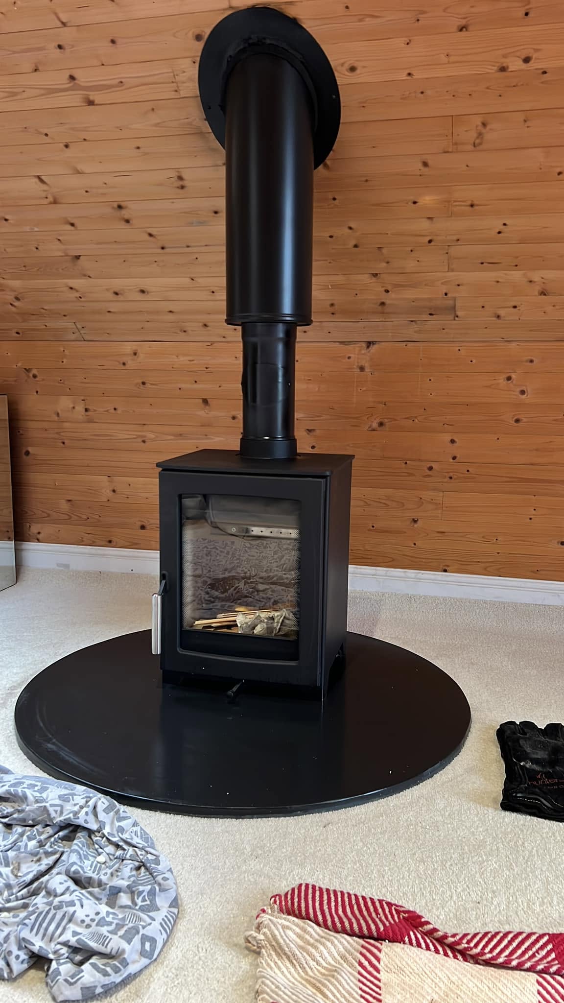 Freestanding wood burner with twin wall flue in a timber-clad room