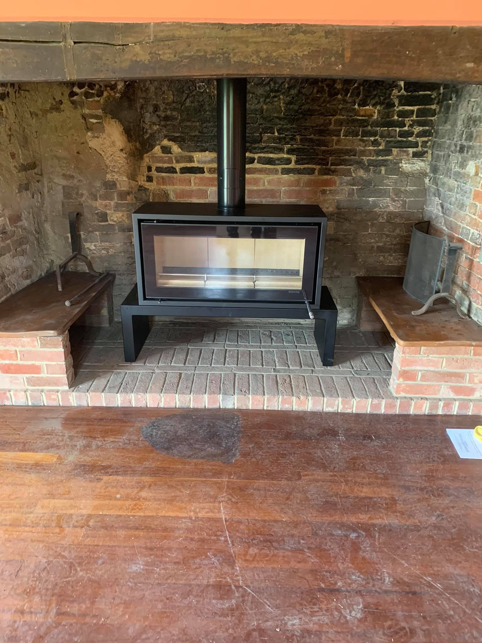 Modern wood-burning stove installed in a traditional brick inglenook fireplace